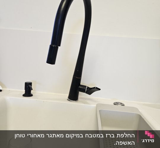 ברז שחור מעל כיור לבן עם כוס זכוכית